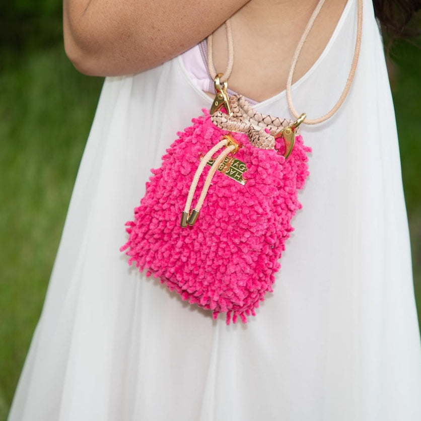 Pink fluffy handbag with gold handles on a white background