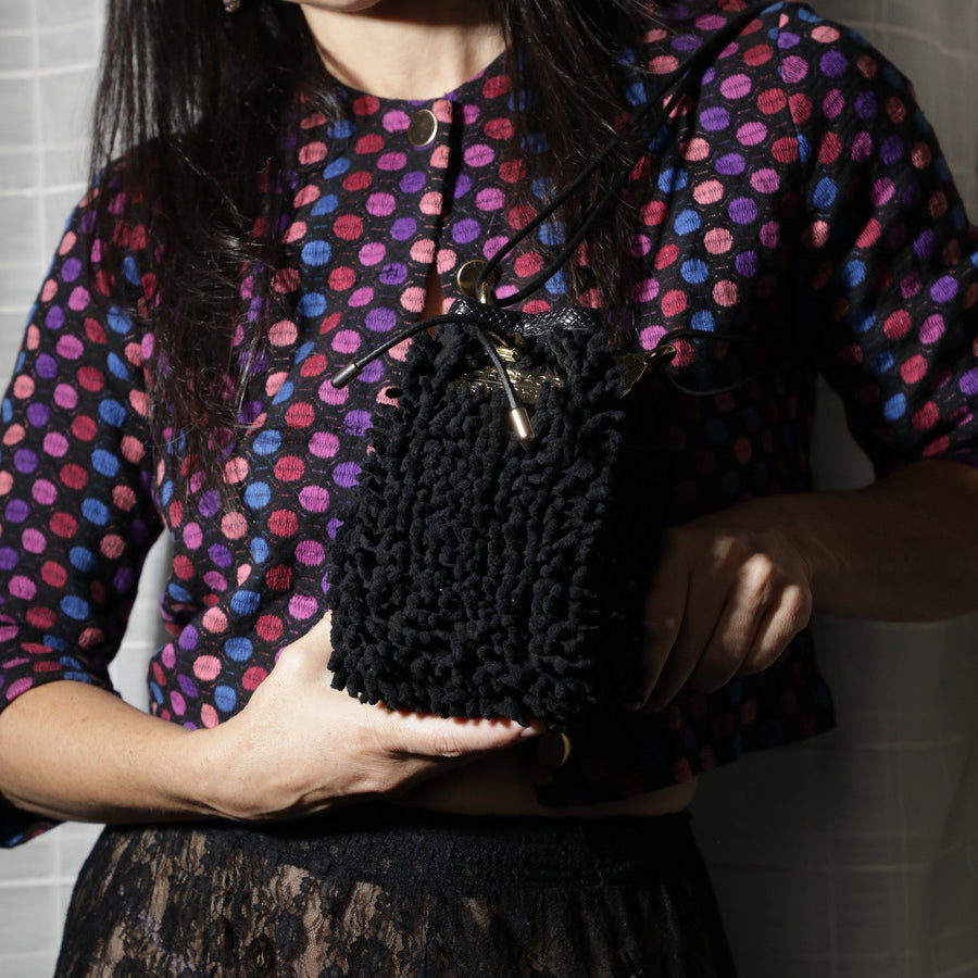 Black textured mini handbag with gold hardware worn crossbody with interior zipper pocket detail