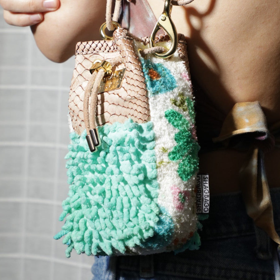 Multicolored textured drawstring bag with a gold lock on a light gray background