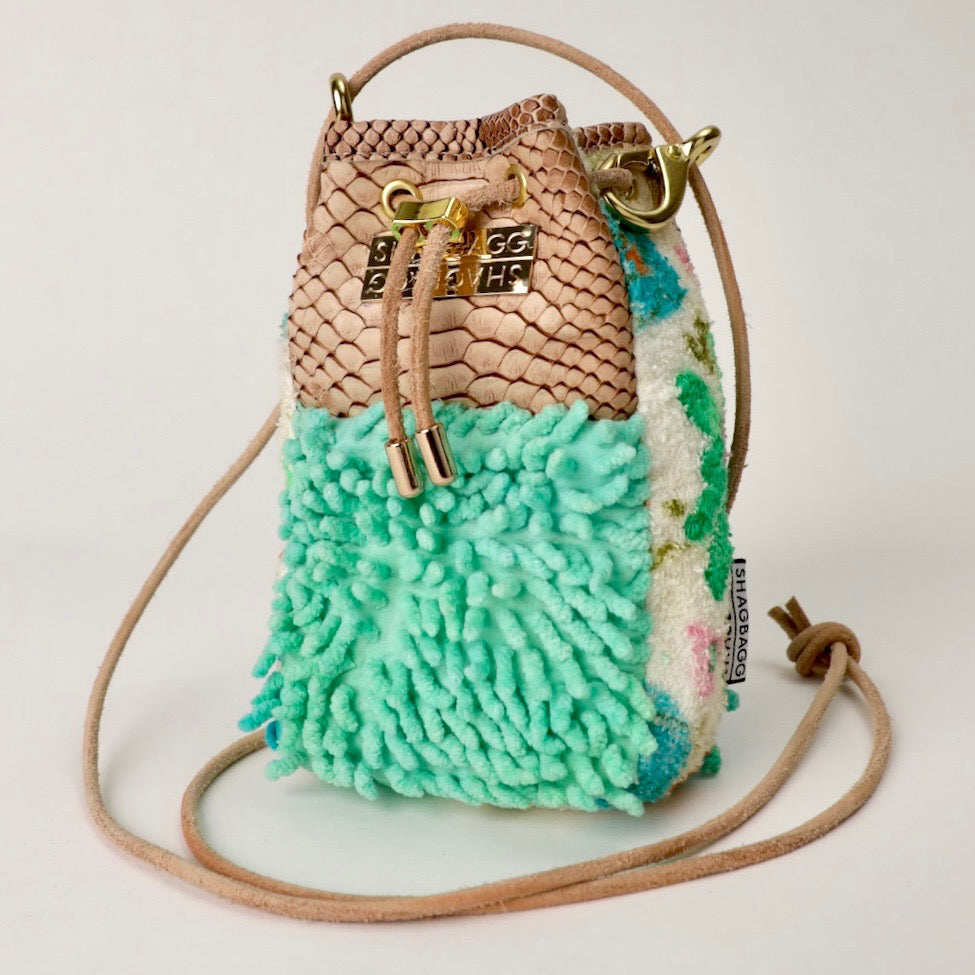 Multicolored textured drawstring bag with a gold lock on a light gray background
