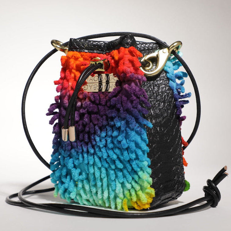 Colorful woven bag with a black strap on a light gray background