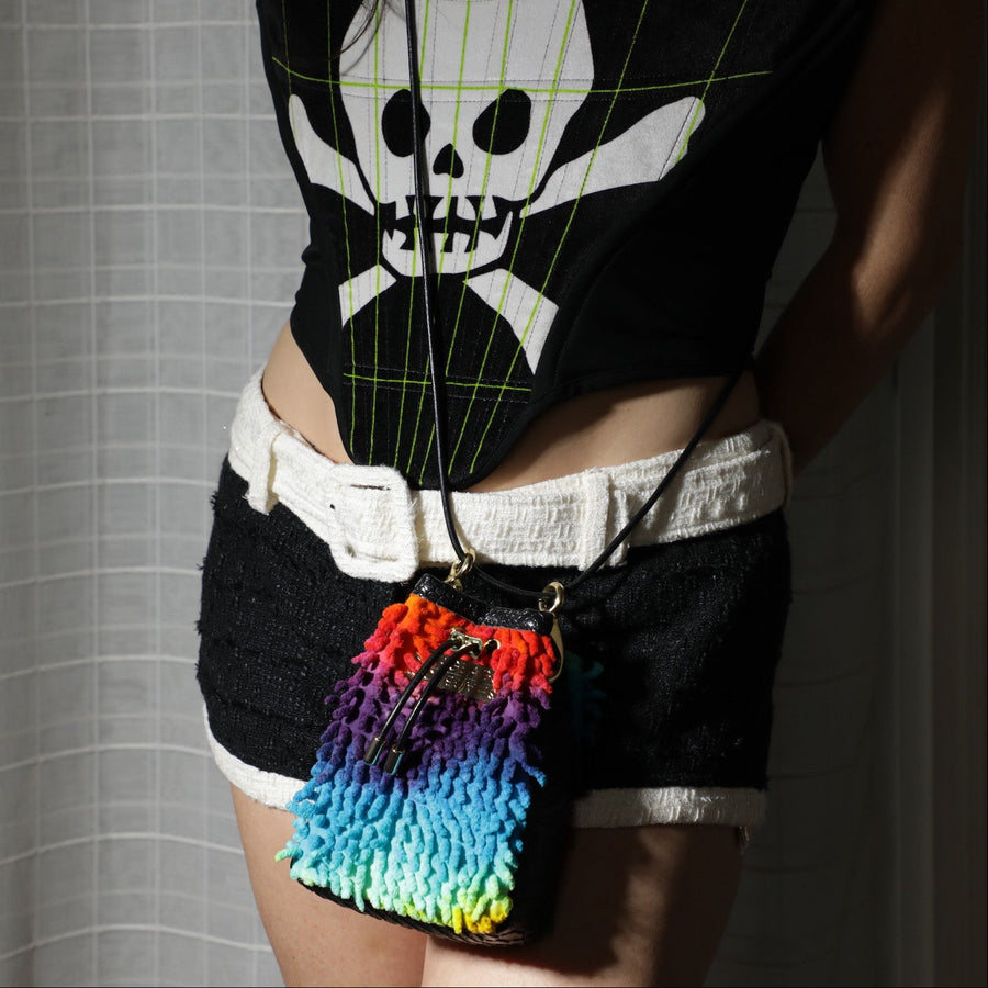 Colorful woven bag with a black strap on a light gray background