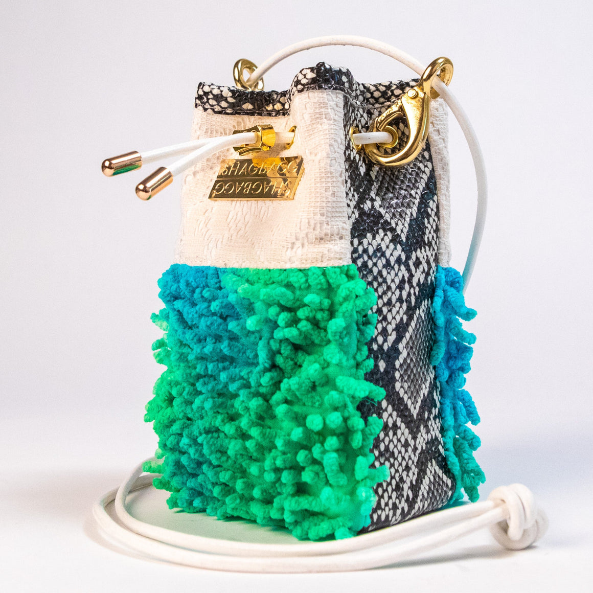SHAGBAGG Mermaid Mini crossbody bag hanging — electric green and teal tie-dye SHAG, vintage lace, faux python, white leather strap, gold hardware