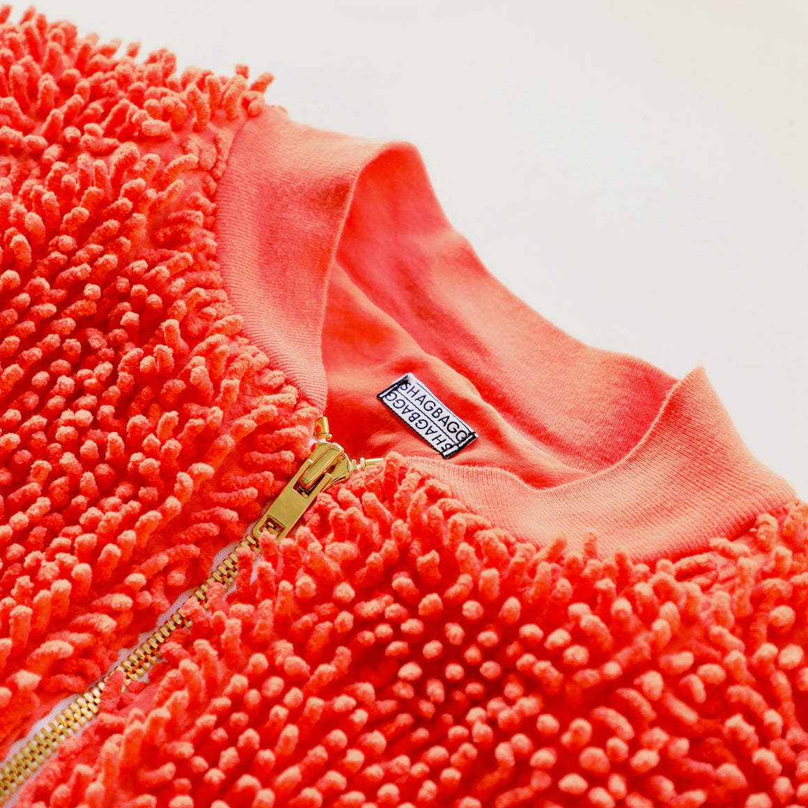 Close-up detail of the Tangerine SHAG bomber jacket collar and gold zipper by SHAGBAGG.